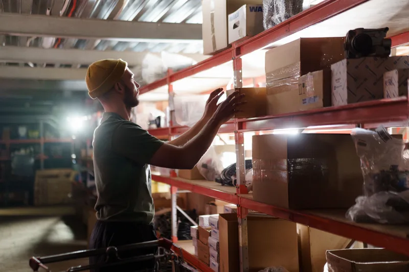 Una persona retira una caja de una estantería de inventario