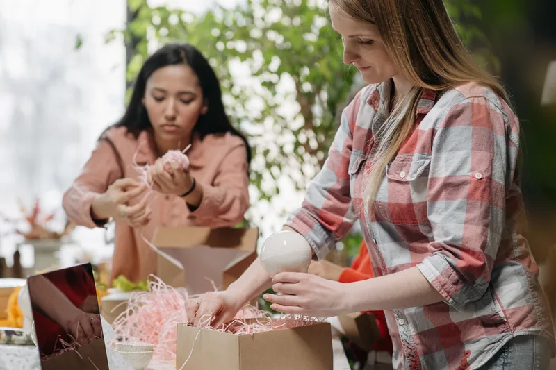 Dos personas preparan un pedido con cajas y material de embalaje