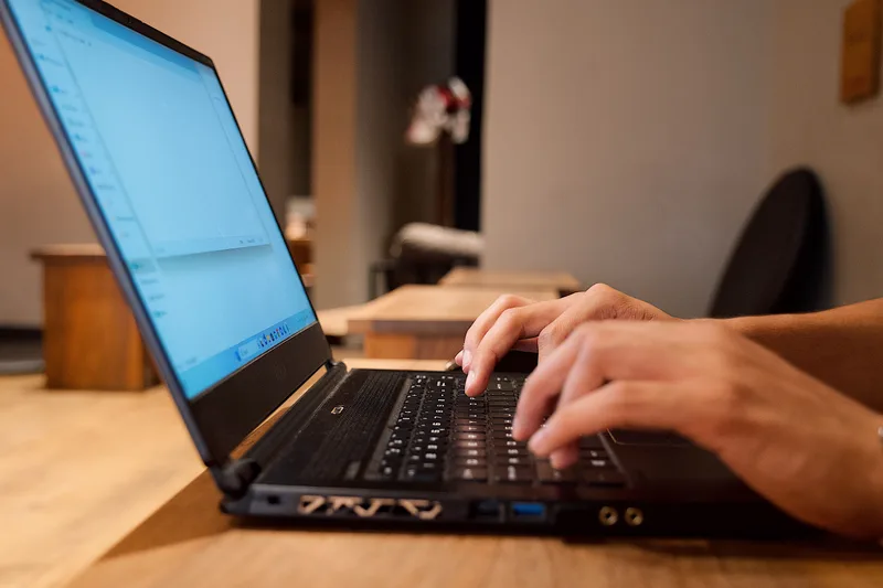 Manos trabajando en un computador portátil sobre un escritorio